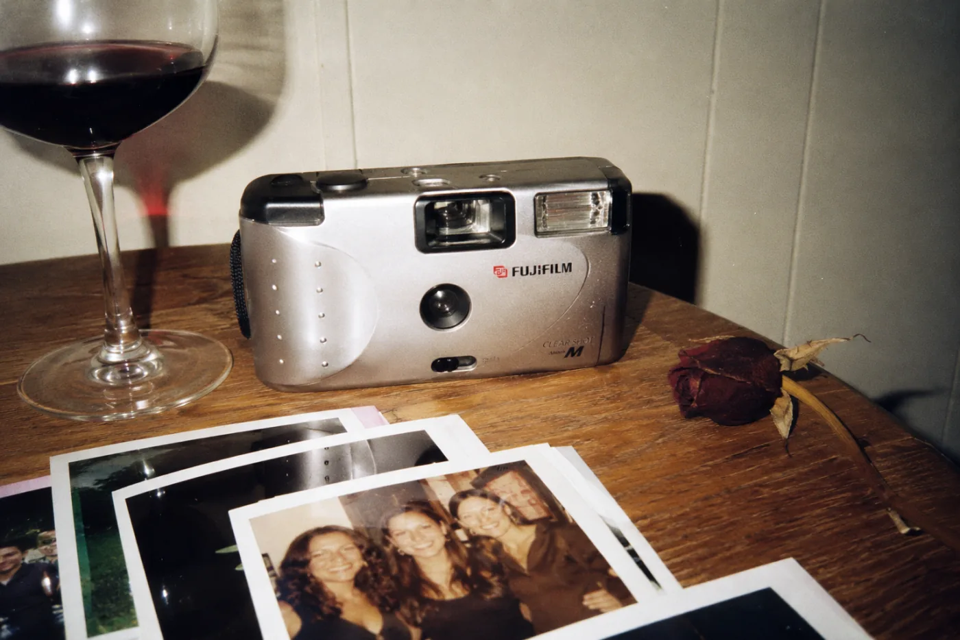 Una cámara desechable Fujifilm sobre una mesa, junto a fotos ya reveladas